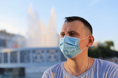Happy smiling young tourist guy dressed in casual clothes and a medical surgical mask protecting his face during the covid-19 pandemic.の写真素材