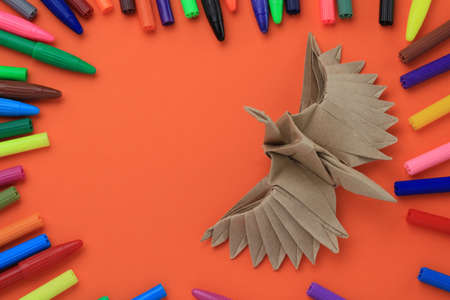 Origami paper bird mockup. Selective focus. A lot of multi-colored felt-tip pens on a blurry backgroundの写真素材