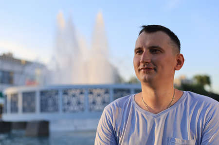 Happy smiling young guy tourist in an urban environment. Toned background.