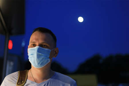 Happy smiling young tourist guy dressed in casual clothes and a medical surgical mask protecting his...