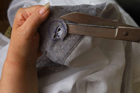 The process of scissors cutting holes for eyelets curtains.