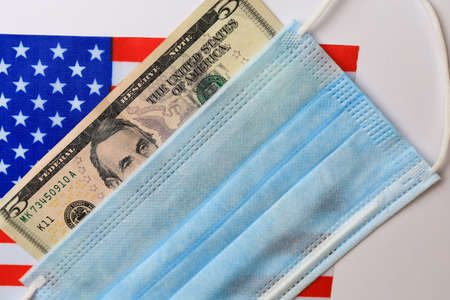 5 dollar bill with a covered face mask on the background of the American flag.の写真素材