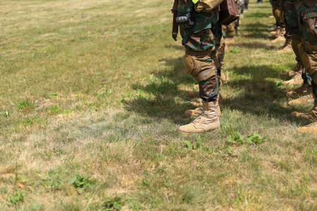 Legs of real soldiers in military boots and clothes standing in formation on the grass. Background with copyspace.の写真素材