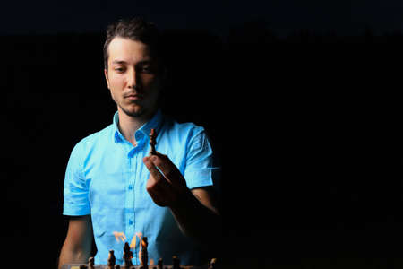 White Caucasian young man or adult guy and a burning chessboard. Dark low key, black background,...