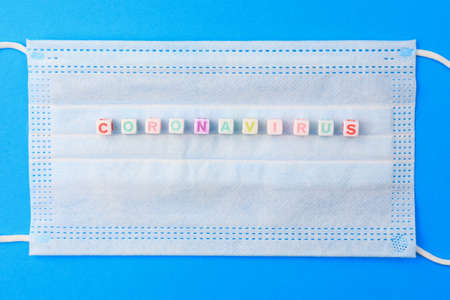 Cubes form the text Coronavirus on the background of a medical surgical mask.の写真素材