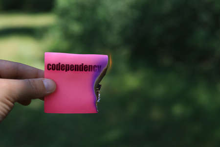 Word or text codependency. Burning sticker in hand.