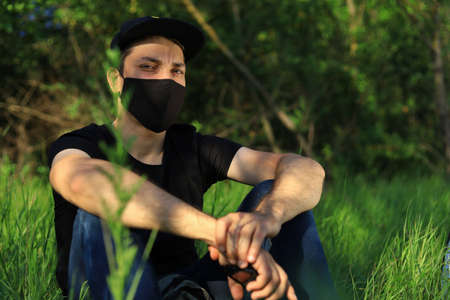 Young white Caucasian man in protective mask on blurred green forest background.