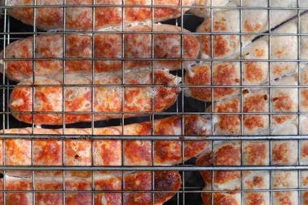 Cooking homemade sausages over the fire. Selective focus with blurred backgroundの写真素材