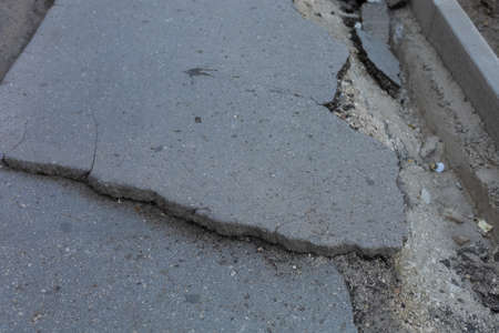 Very bad urban environment with ruined and broken asphalt on the sidewalk. Background