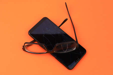 Broken glasses and smartphone. Selective focus. Backgroundの写真素材