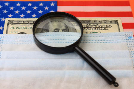 US dollars and a magnifying glass as a symbol of the search for money. The concept of investment and...