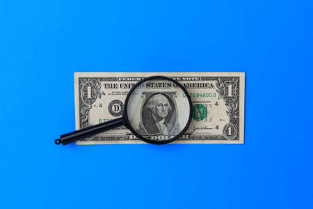 US dollars and a magnifying glass as a symbol of the search for money. The concept of investment and overcoming the crisis.の写真素材