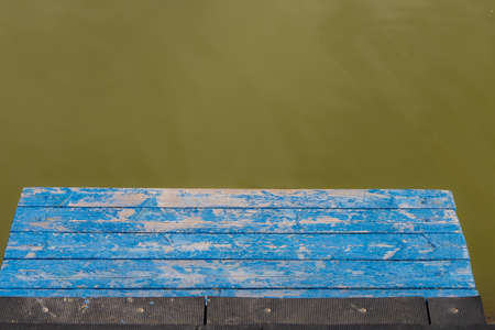 Wooden pier for boats and canoes. Turbid green water of a lake or river. Backgroundの写真素材
