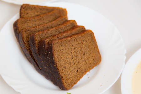 Sliced black bread on a plate. Culinary background with selective focus and blurred background.の写真素材