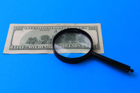 US dollars and a magnifying glass as a symbol of the search for money. The concept of investment and overcoming the crisis.の写真素材