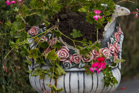 Suffered from vandals bowl or a vase of flowers. Flowerbed broken by hooligans in an urban environment. Backgroundの写真素材