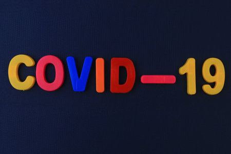 A word or text Covid-19 written in a childrens alphabet with classic letters on a magnet.の写真素材