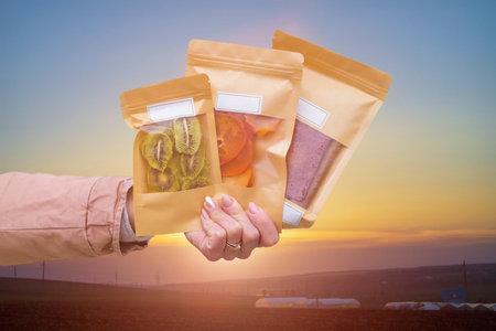 Dried fruits packaged in eco-friendly paper bags in hand. Pastila, persimmon and kiwi. Healthy desserts concept. Natural substitutes for sugar in the diet.の写真素材