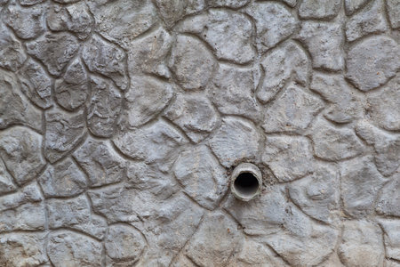 Downpipe in the wall with imitation of a wild stone. Backgroundの写真素材