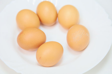 Farm chicken eggs in a white plate. Selective focus with blurred backgrounds and shallow depth of...