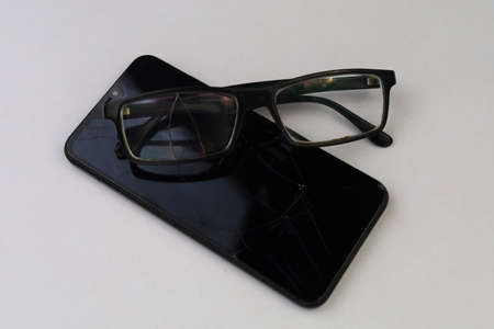 Broken glasses and smartphone. Selective focus. Background