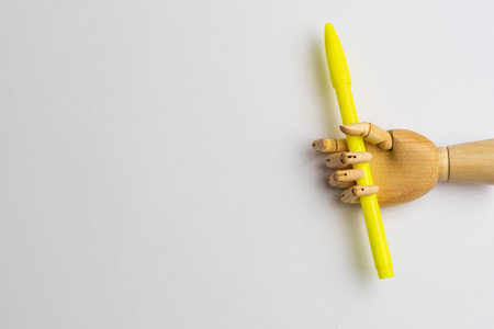 Wooden hand with a bright felt-tip pen on a light background with a place or copyspace for an inscription or text.の写真素材