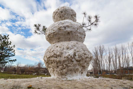 A huge spring snowman in a melted meadow. Background with copy space for lettering or textの写真素材