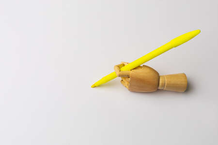 Wooden hand with a bright felt-tip pen on a light background with a place or copyspace for an inscription or text.の写真素材