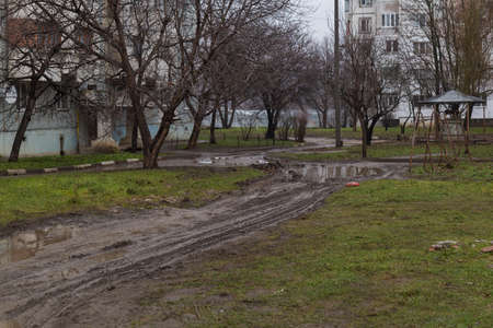 A very muddy road with puddles and swamps along the high rise building. Selective focus backgroundの写真素材
