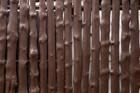 Rough wooden fence made of painted trunks of thin trees with knots. Backgroundの写真素材