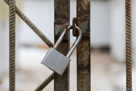 Padlock on a metal fence. Symbol for safety or restrictions and lockdown. Selective focus