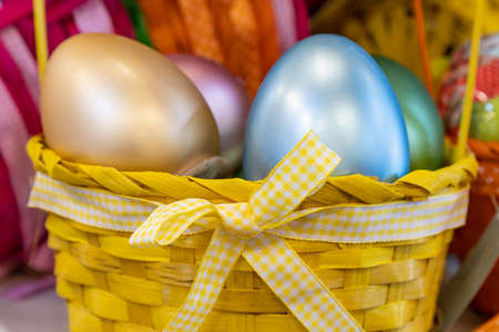 Bow on a basket close up. Easter colored eggs defocused on a blurred background. Background with...