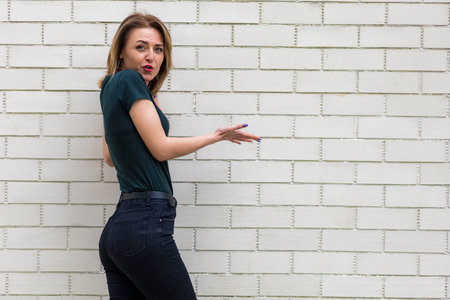 Portrait of a young woman on the background of a light brick wall with a copy spaceの写真素材