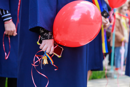 The graduate holds a bell in her hand as a symbol of the last bell. Graduation day.の写真素材