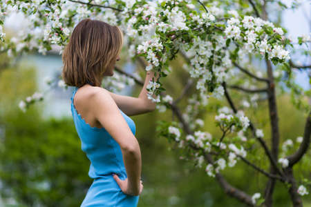 A young woman with a good slender figure stands with her back. Blurred park background. Copy space for text or inscriptionの写真素材