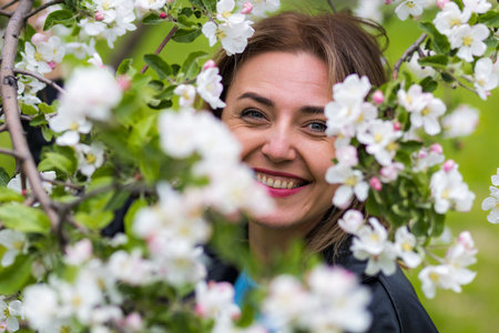 Portrait of a young happy woman of thirty plus years old on a blurred background of flowering trees....