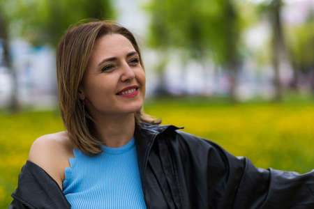 Portrait of a happy and free woman on a blurred green background of a park or forest. Background...