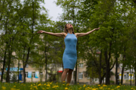 Portrait of a happy and free woman on a blurred green background of a park or forest. Background with copy space for text or letteringの写真素材