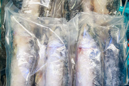 Plastic package with frozen fish products. Goods in the freezer of the store fridge. Close-up...