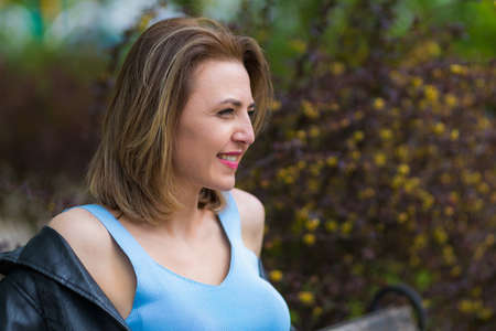 Portrait of a happy and free woman on a blurred green background of a park or forest. Background...