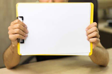 Tablet with a blank A4 sheet in hand. Abstract background with copy space or mockup for design.の写真素材