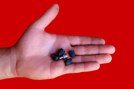 Hand palm with nipple caps from the car wheel. Air leakage protection from tires. Toned background with selective focus and copy space for text or lettering.の写真素材