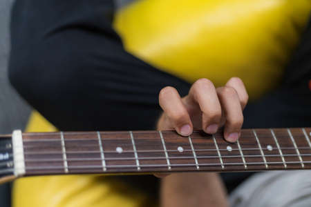 The guitarists fingers are on the neck of the guitar. View from above. Selective focus with blurred background for copy space.の写真素材