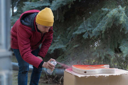 A man applies a spray can on a homemade product. Selective focus backgroundの写真素材