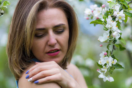 Portrait of a young happy woman of thirty plus years old on a blurred background of flowering trees. Copyspace for textの写真素材
