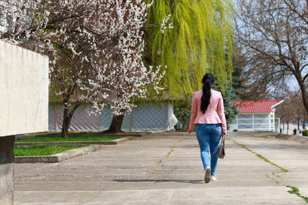 A woman walks through the city, view from the back in an urban environment. Background with copy space for textの写真素材