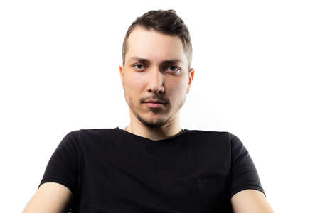 Young handsome man looks seriously and penetratingly into the eyes on a light backgroundの写真素材