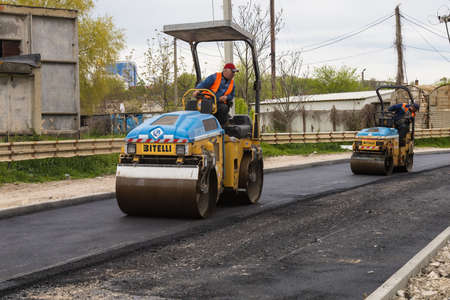 Asphalt paver at road repair. Background with copy space for text or inscriptions. Illustrative editorial. May 7, 2021 Balti Moldova.のeditorial素材