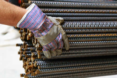 The hand in the signet unloads the reinforcement for the slab foundation. Background with selective...