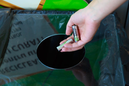 Womans hand throws the batteries into a special trash can for the separate collection of hazardous waste. Environment ecology concept. Illustrative editorial. June 8, 2021 Balti Moldova.のeditorial素材